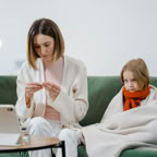 A mother and daughter engage in a telehealth session at home for health concerns.