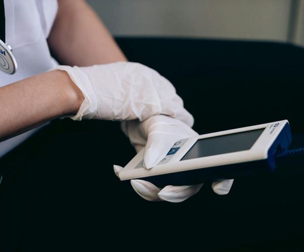 Healthcare worker with gloves using medical device indoors.